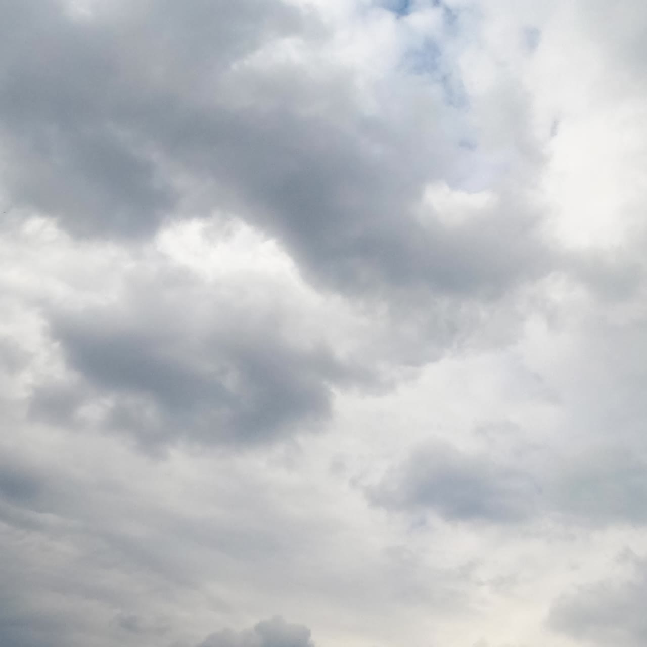Langit Azure jarang terlihat di balik lanskap awan abu-abu. Awan abu-abu yang menumpuk di atmosfer. Tampilan sudut rendah. Selang waktu