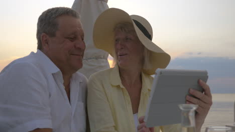 mature couple watching photos in tablet and laughing