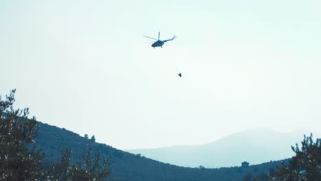 chopper in distant flying away after dropping water on forest fire