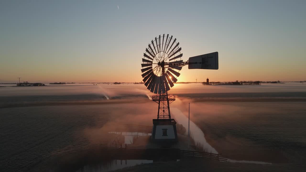 Scatto aereo di un vecchio mulino a vento in un campo nebbioso al mattino, Frisia, Paesi Bassi