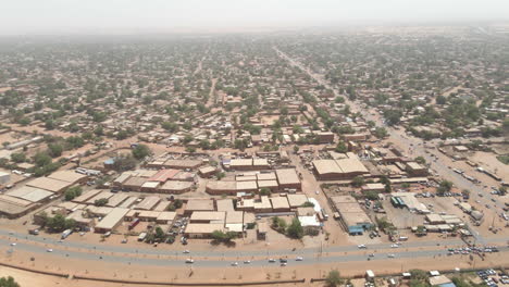 drone moves backward over a nigerian city during daytime, revealing a wide urban landscape and architectural layout from above