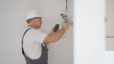 a man electrician checks the work of transformers to illuminate the low-voltage network in the apartment