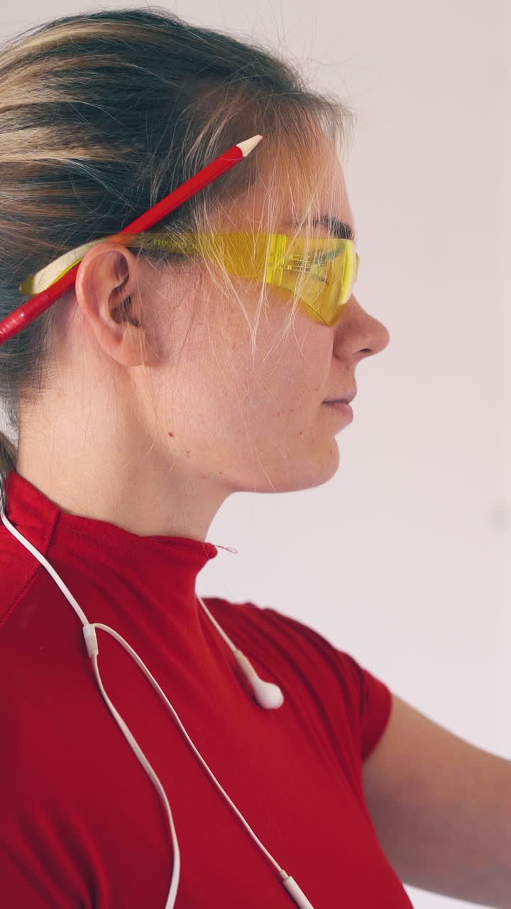 CU, Dolly cam: happy woman with earphones and googles checks wall level using modern instrument in renewing room closeup