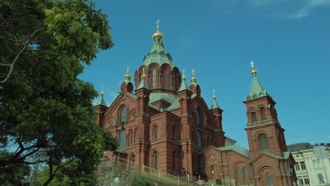parallax shot of uspenski cathedral revealed behind tree leaves, helsinki tourism