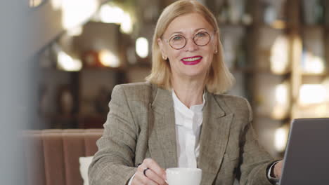 portrait of smiling senior businesswoman with laptop in restaurant