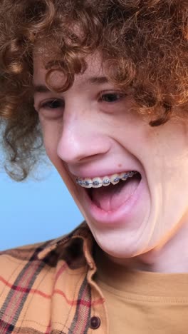 cute young happy student on blue background looking at phone cute young happy student on blue background looking at phone curly redhaired guy is crazy happy internet search technologies