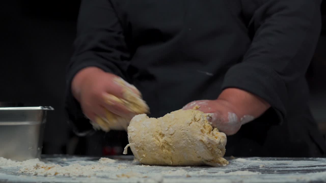 Chef baker kneading the dough at gourmet restaurant kitchen over stainless steel table messy mix flour for bread buns
