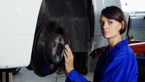 female mechanic examining car wheel brake disc