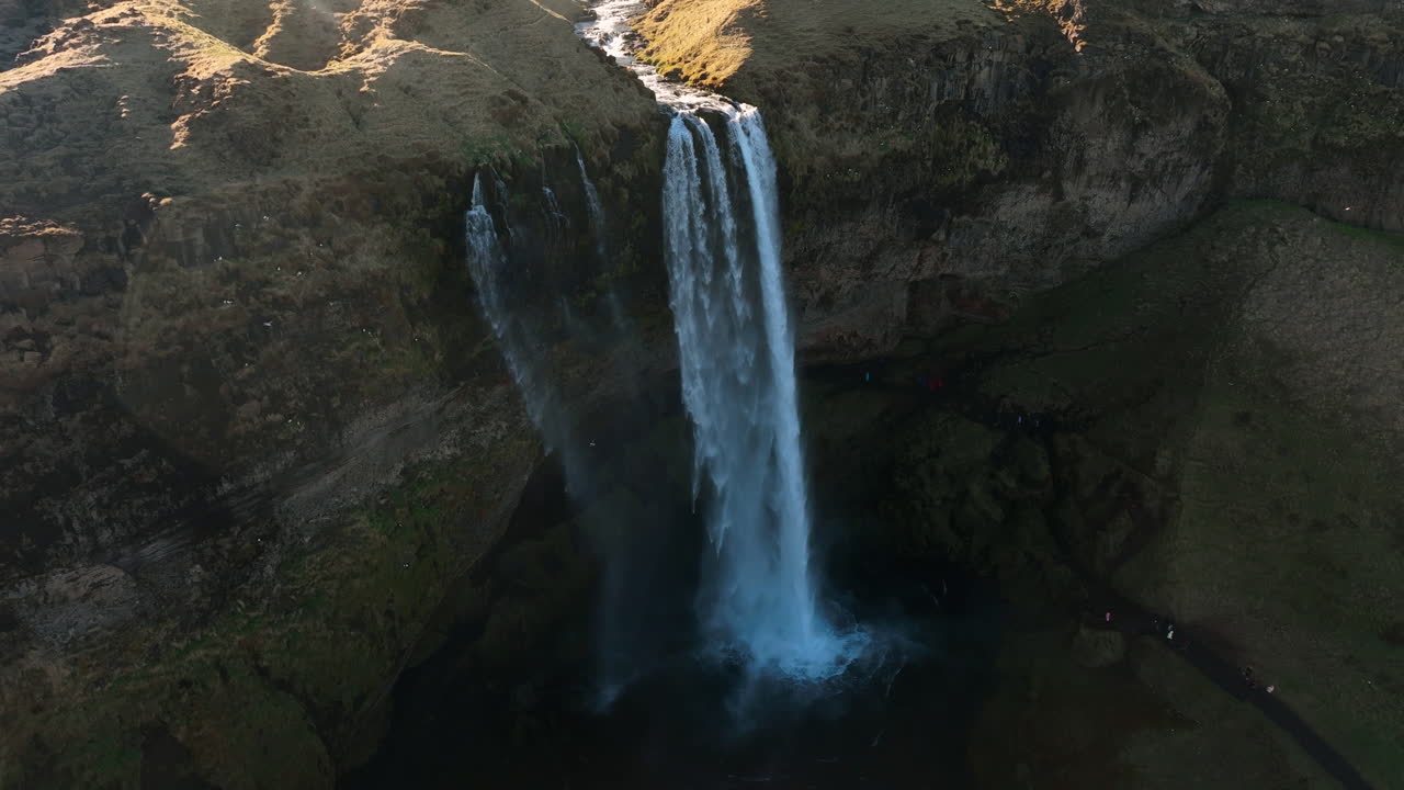 vista aérea hacia atrás lejos de una cascada, soleado, día de otoño en islandia