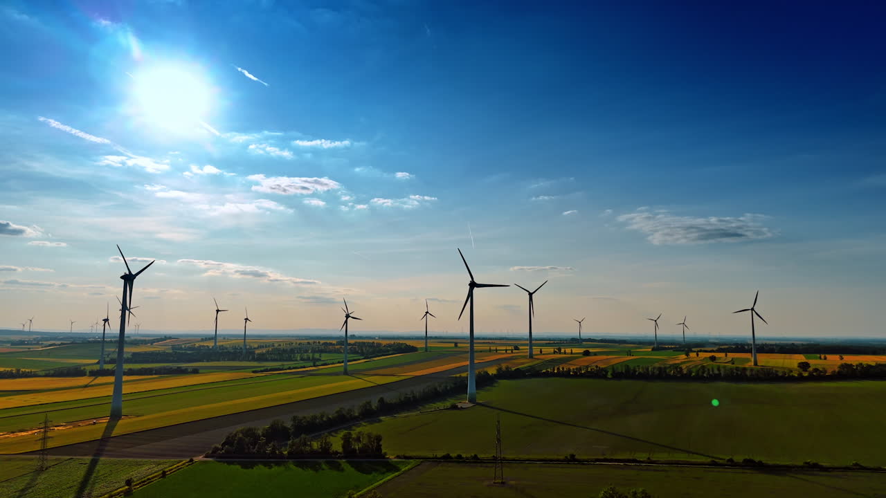 Turbines produce green energy. Wind turbines stand tall in a vast landscape, producing clean energy under a clear blue sky during the daytime