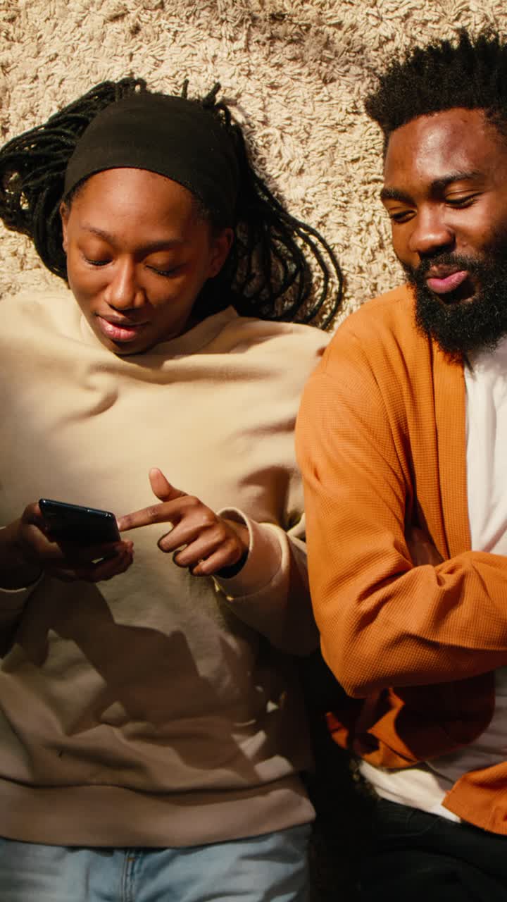 Vertical Video Top down view of black man and woman laughing together on hallway floor