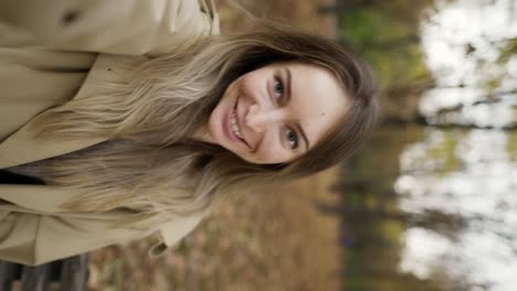 blonde woman taking selfie photo on smartphone outdoors in park while walking