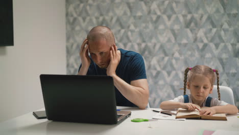 father-tries-to-concentrate-daughter-does-homework-at-table