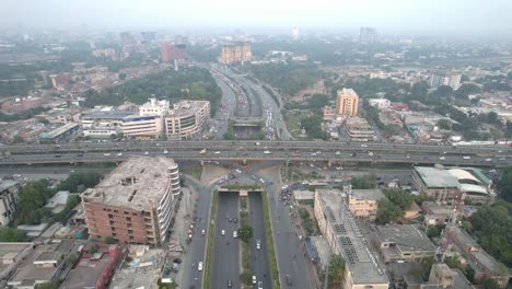 Toma-Aérea-De-Automóviles-Que-Viajan-Por-El-Paso-Elevado-De-La-Autopista-Y-El-Paso-Subterráneo-En-La-Ciudad-Urbana