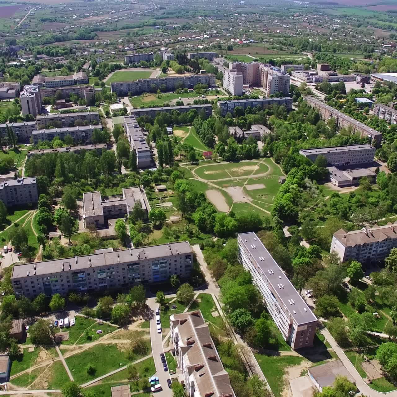 Multi-storied blocks of flats in the residential area. Lots of green trees growing among the houses. River at backdrop