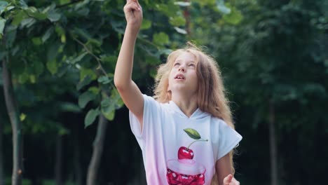 cute child is playing with a windmill. portrait of a girl in the park near the trees
