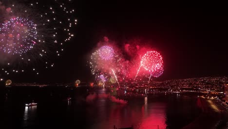 dolly in bird's-eye view of ships launching fireworks in a coordinated manner in valparaiso at night, chile