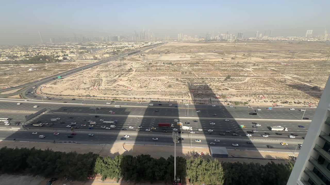 Veicoli che si muovono lungo Al Khail Road a Dubai, mentre lo skyline della città si erge sullo sfondo, illustrando la vita quotidiana negli Emirati Arabi Uniti.