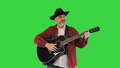 man in cowboy hat playing on guitar and singing on a green screen, chroma key