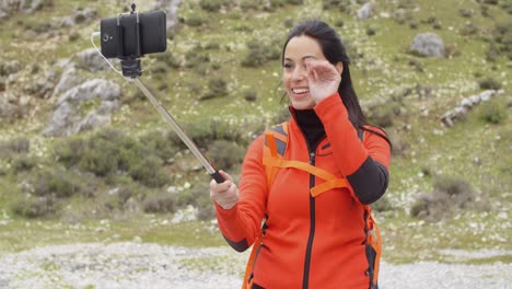 Lächelnder-Junger-Rucksacktourist-Mit-Einem-Selfie-Stick