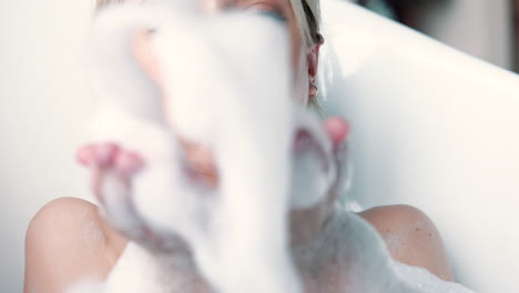 woman lying in bathtub full of foam