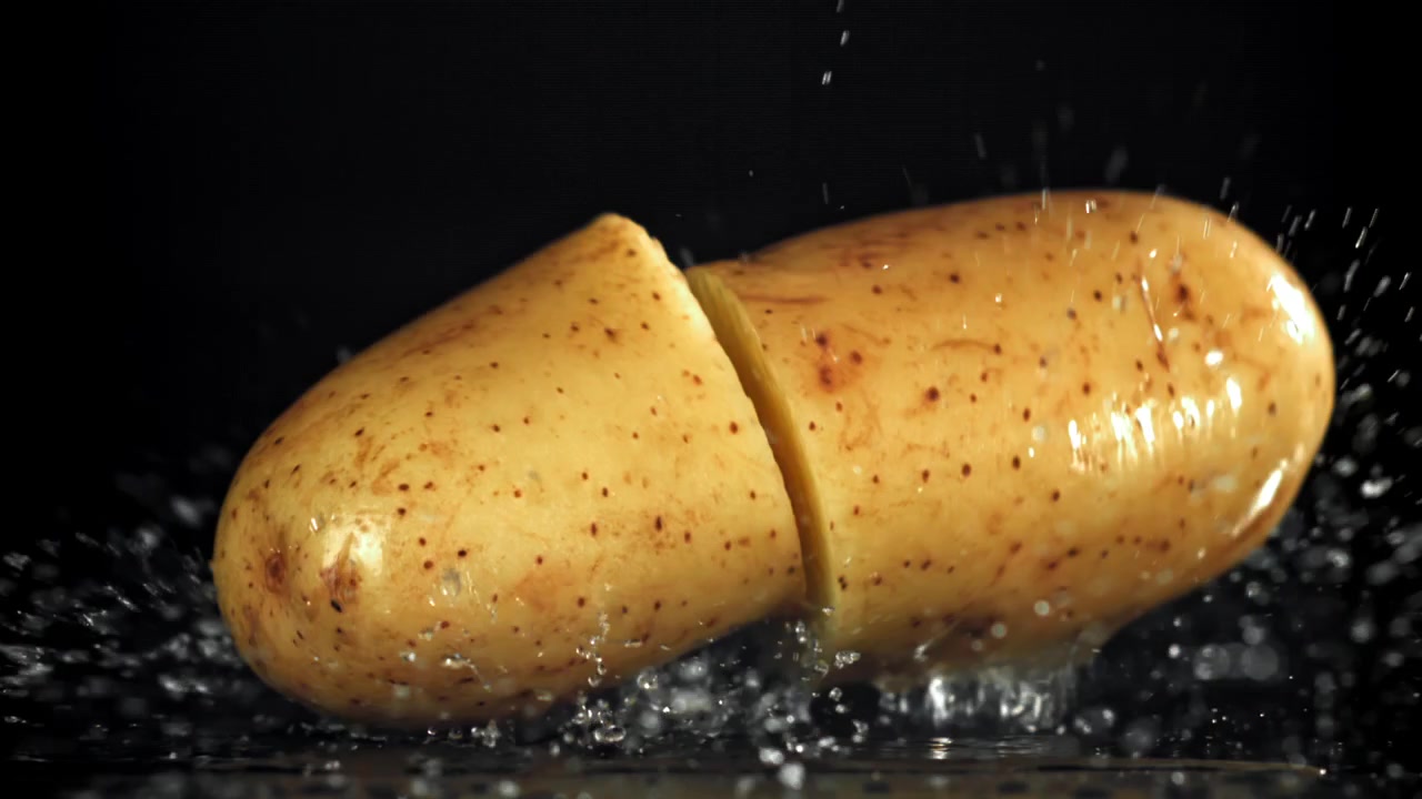 Rallentatore di una patata fresca che cade e schizza nell'acqua, per poi separarsi.