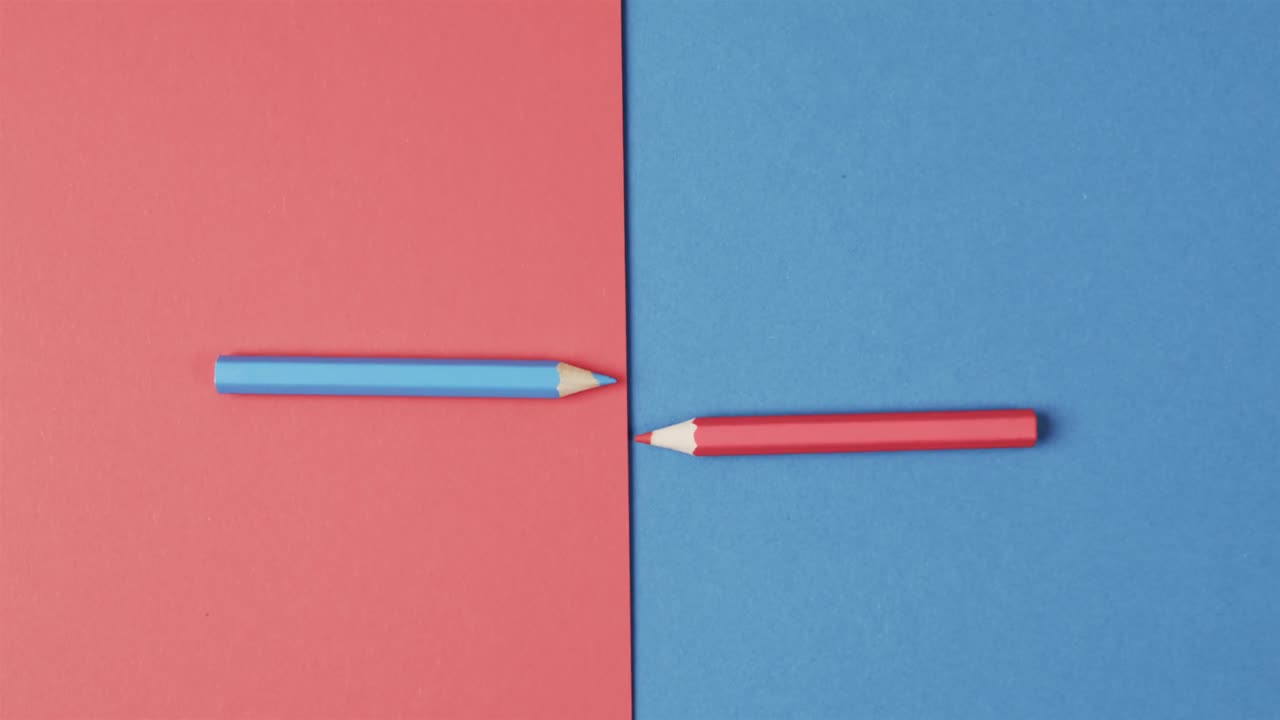 vista aérea de lápices de colores azules y rojos dispuestos sobre fondo rojo y azul, en cámara lenta