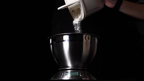 person pouring flour in bowl on digital scale