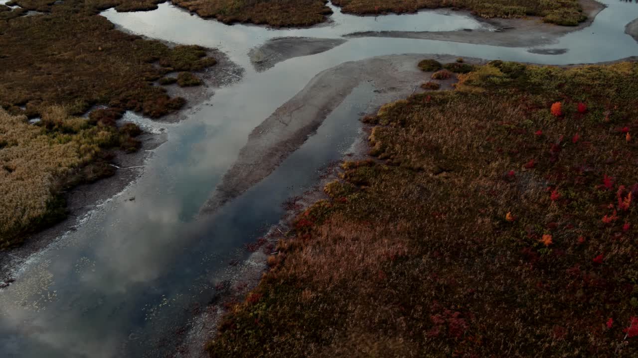 un río poco profundo rodeado de plantas otoñales en el prado en magog, quebec, canadá en una puesta de sol