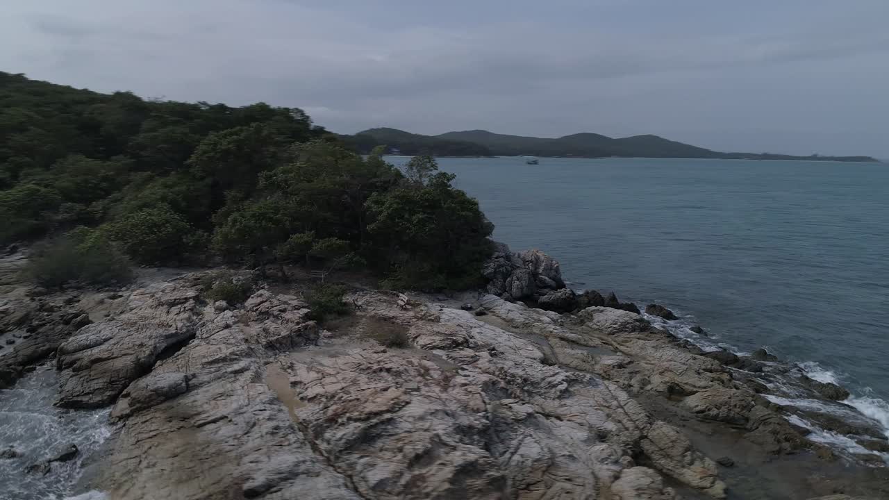 바위가 많은 노두, 작은 어선, 바다 위의 드론 비행