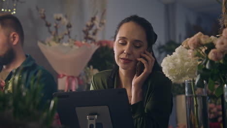 florista habla por teléfono con el cliente y usa una tableta