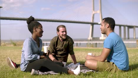 cheerful employees talking during coffee break on lawn.