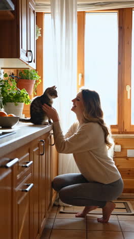 woman playing with her kitten in the kitchen