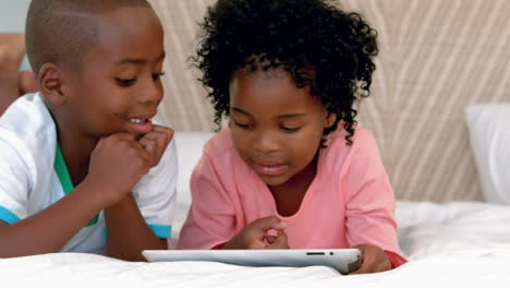 Happy-siblings-using-tablet-on-bed