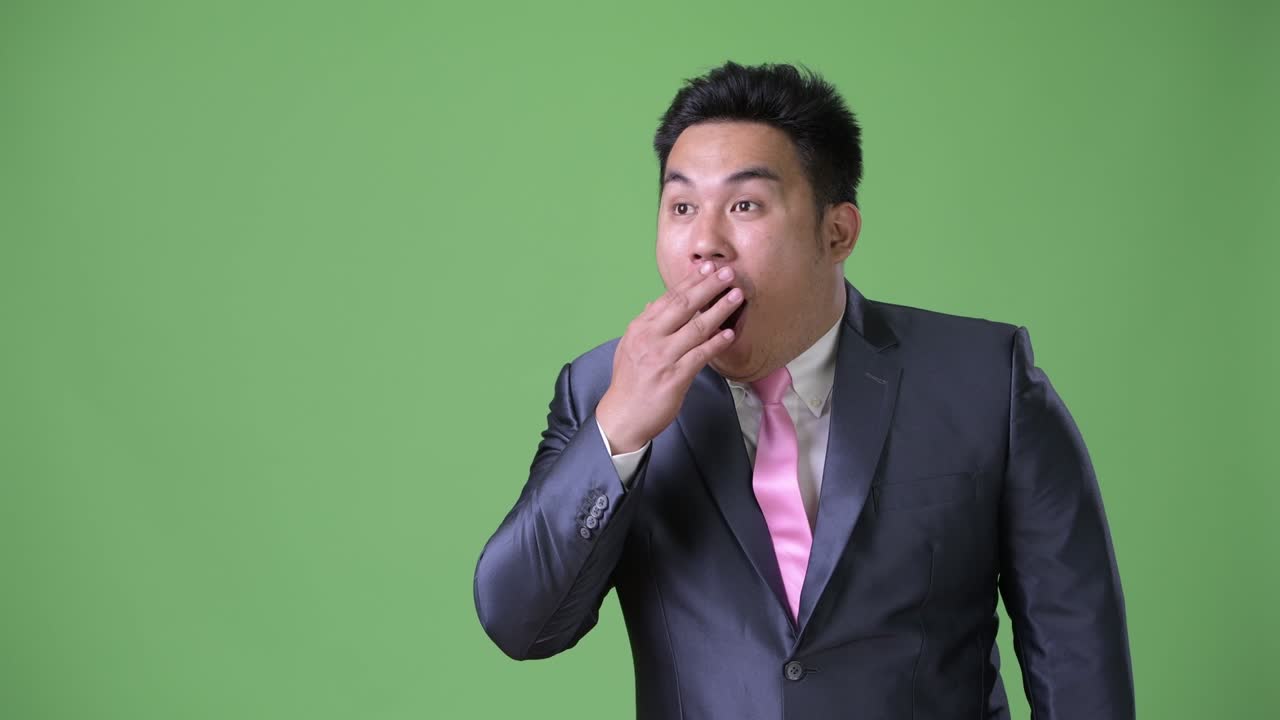 초록색 배경에 젊은 잘생긴 과체중 아시아 사업가