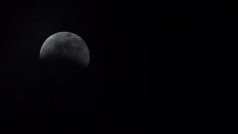 nubes delgadas revelan lentamente una luna llena durante un eclipse lunar