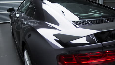 lights reflect on sleek body of a new car parked in the showroom. - side view, close up