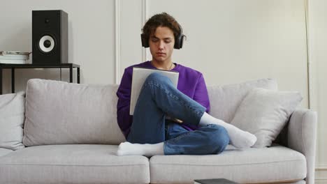 joven estudiando en un sofá con auriculares