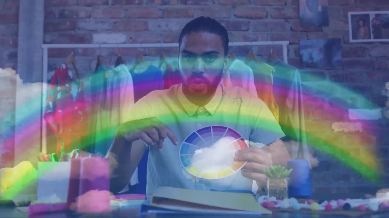 Rainbow light trails against african american male fashion designer holding a color pallete