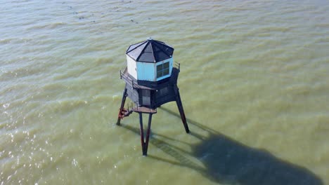 Orbiting-Drone-View-of-Dovercourt-Range-Rear-Lighthouse-On-Stilts-in-the-Sea