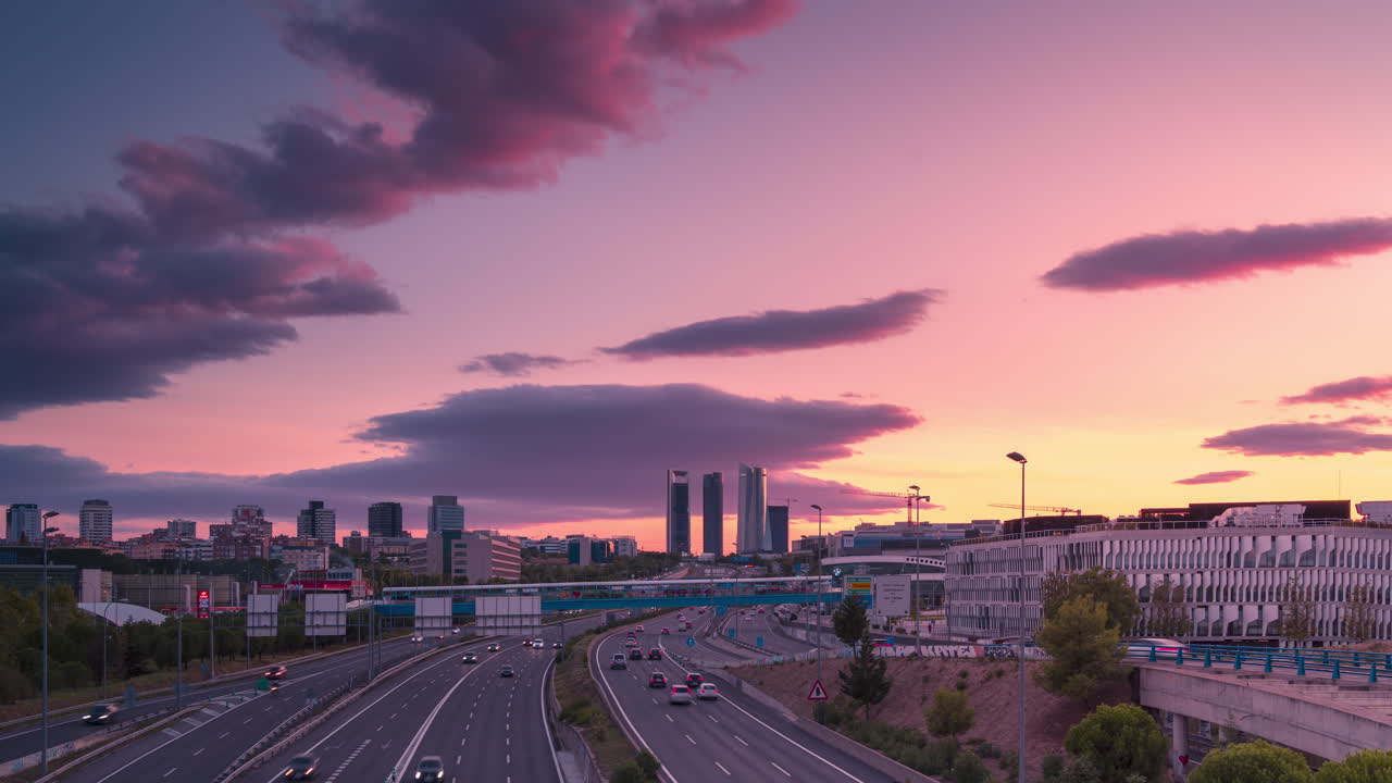 Vista do centro de Madrid com autoestrada que se estende em direção ao pôr do sol com belas nuvens, em timelapse.