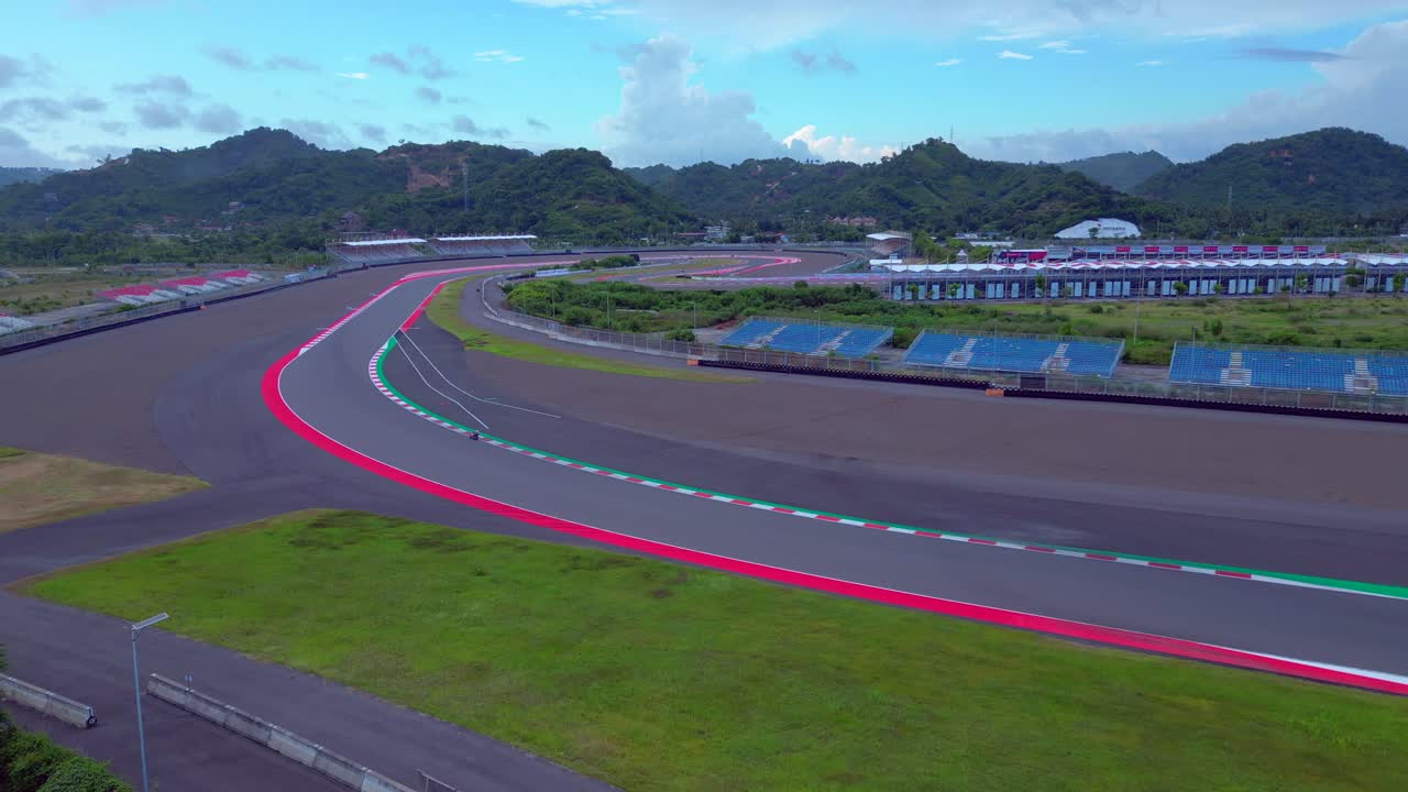 Moto in pista, un concetto di velocità e sport. Vista panoramica del circuito con colline e cielo blu. Incredibile vista aerea panoramica in ascesa da drone.