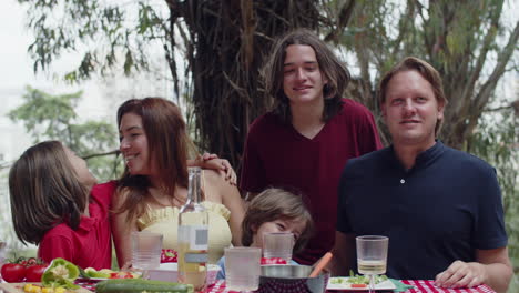 family sitting together at table, hugging, smiling and talking