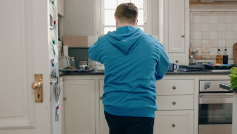 happy teenage boy with down syndrome dancing in kitchen having fun celebrating funny dance enjoying weekend at home