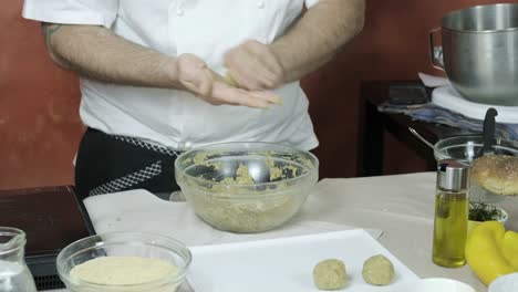 Frontal-view-of-chef-rolling-together-homemade-vegetable-stock-balls-placing-on-parchment-paper