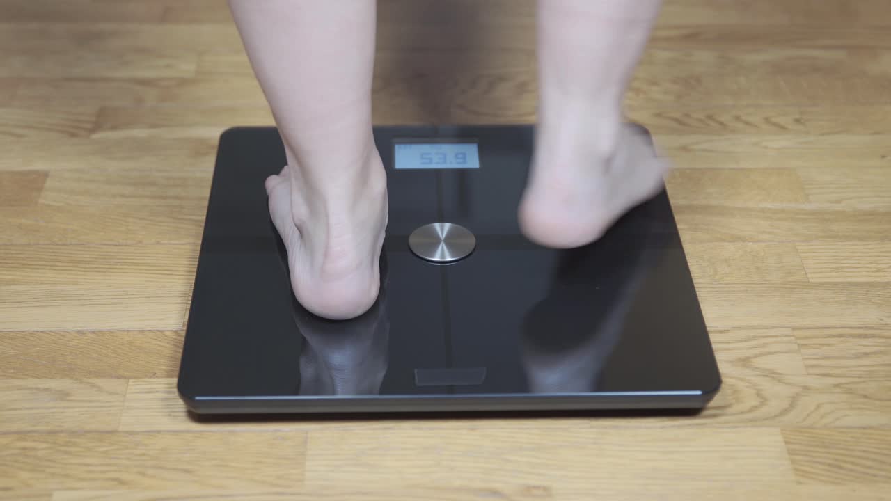 Person Weighing Themselves on a Digital Scale