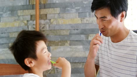 father and son brushing teeth together in bathroom 4k