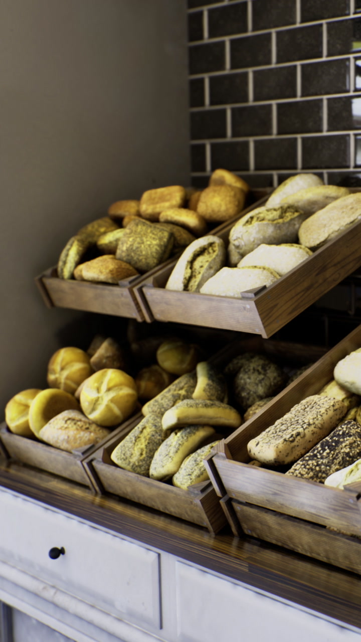 Bakery display shows various types of bread and rolls arranged on shelves