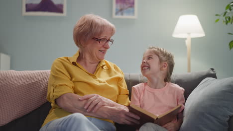 La-Abuela-Y-La-Niña-Se-Ríen-De-Un-Momento-Divertido-En-Un-Libro-En-Casa.