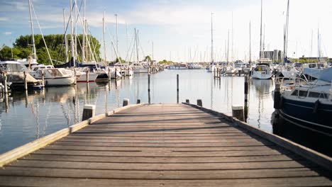 small wooden pier leading towards the waters of a sail boat harbour during sunset in the netherlands